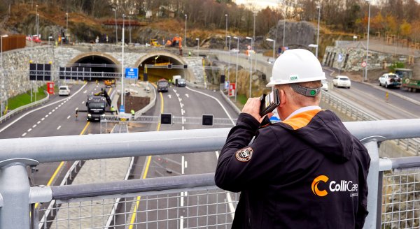 Employee in branded clothes talking on the phone and looking down on the freeway in Norway from a bridge